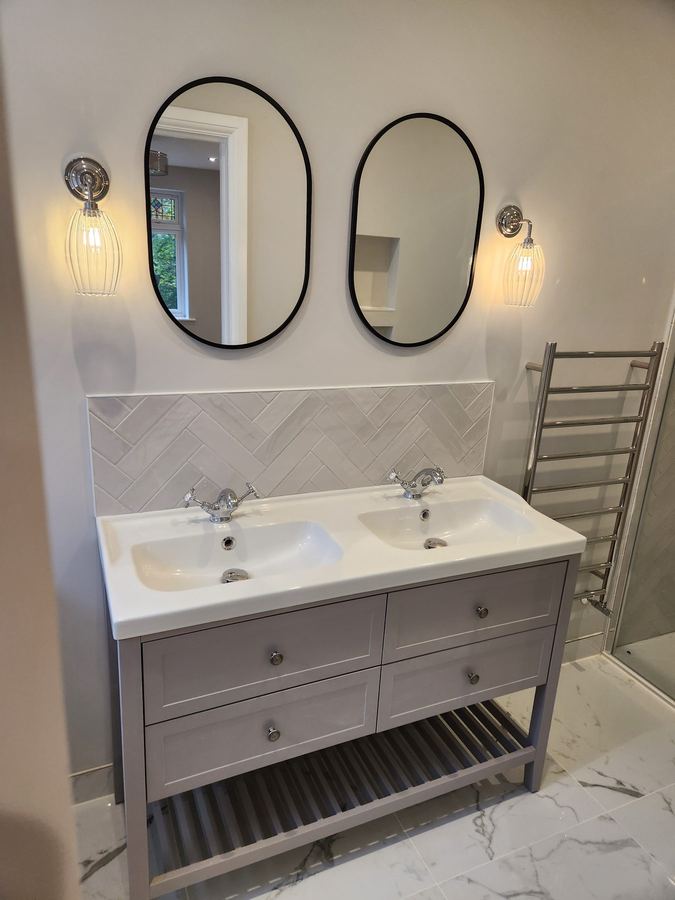 Bathroom with twin basins, oval mirrors and herringbone tiled splashback