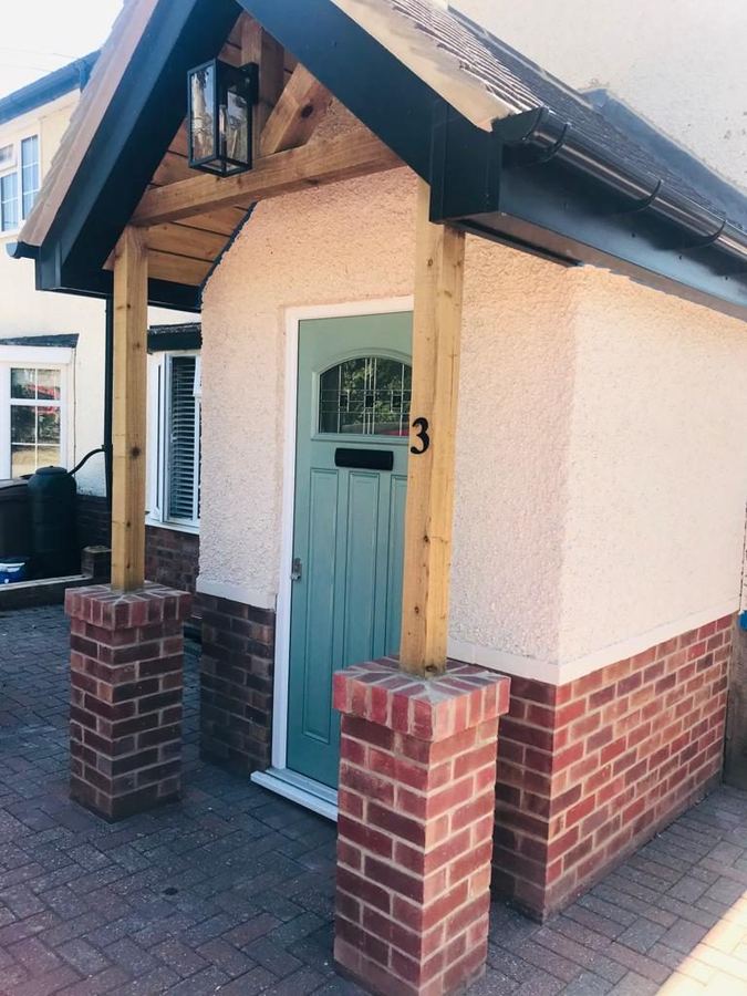 Oak framed porch with brick piers and a painted front door