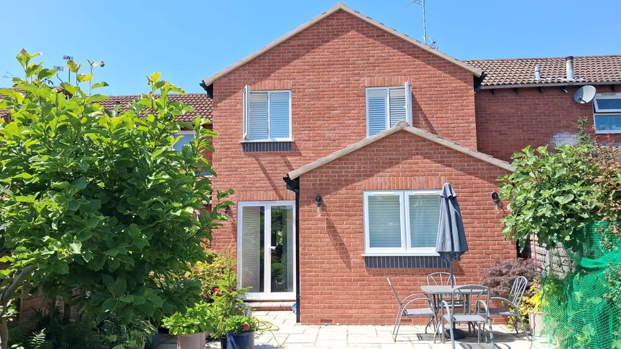 Two storey rear extension in red brick with a patio and garden